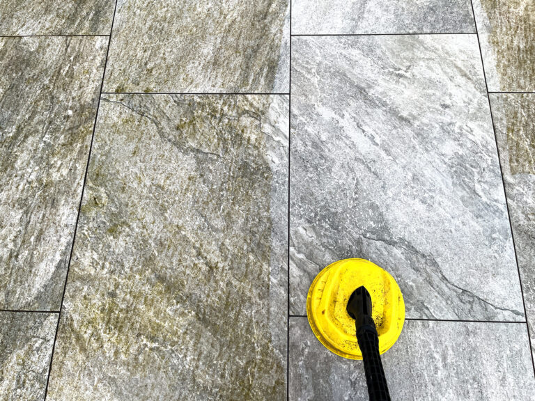 Een vakman die de apparatuur klaarmaakt voor een terras laten reinigen in Almere Poort, op een zonnige middag in een moderne achtertuin.