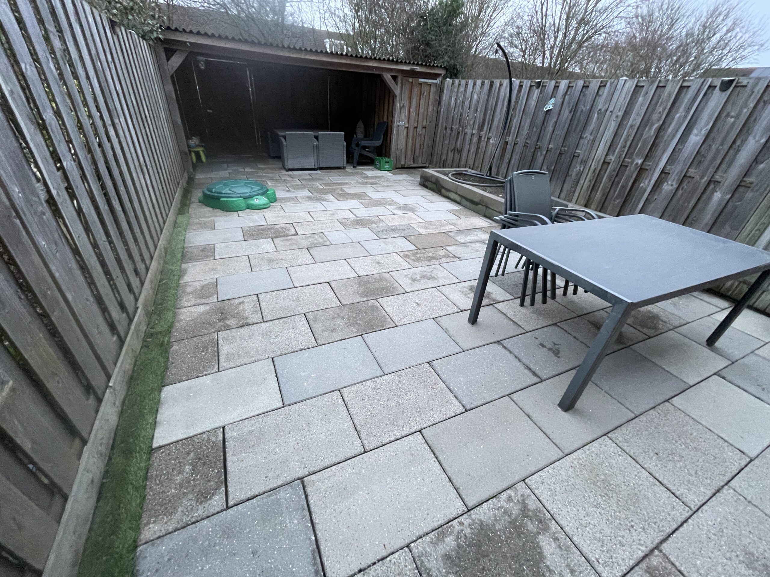 Professioneel terras laten reinigen in de wijk Almere Poort waarbij groene aanslag en mos effectief worden verwijderd van grote tegels.