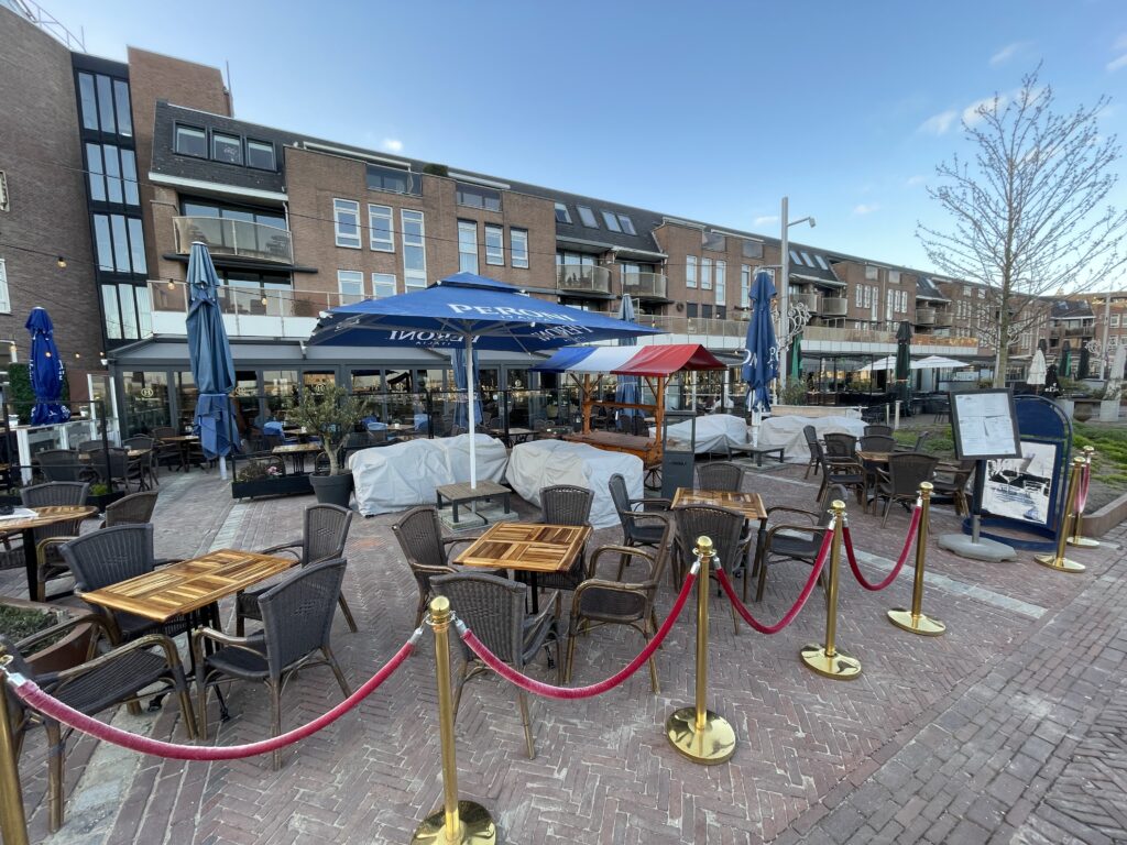 Een visueel contrast tussen een vervuild stenen terras met groene aanslag en een schoon gedeelte na het terras laten reinigen door een specialist.